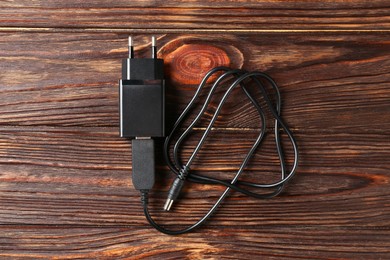 Photo of USB power adapter with charge cable on wooden table, top view