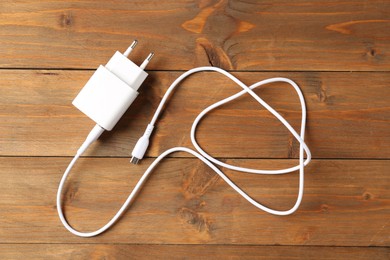 Photo of USB power adapter with charge cable on wooden table, top view