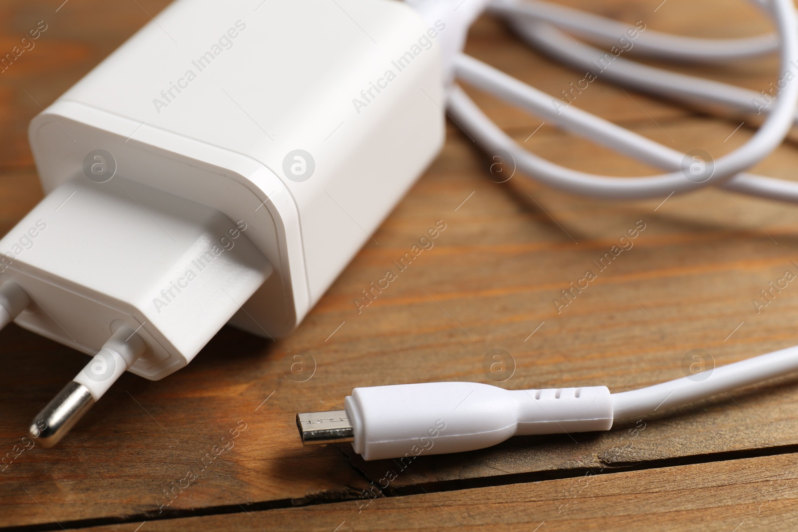 Photo of USB power adapter with charge cable on wooden table, closeup