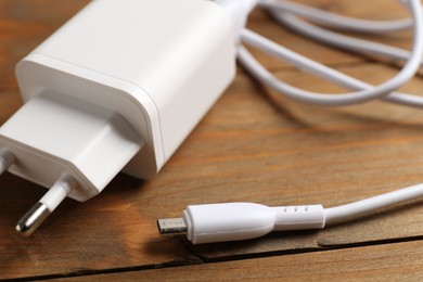 Photo of USB power adapter with charge cable on wooden table, closeup