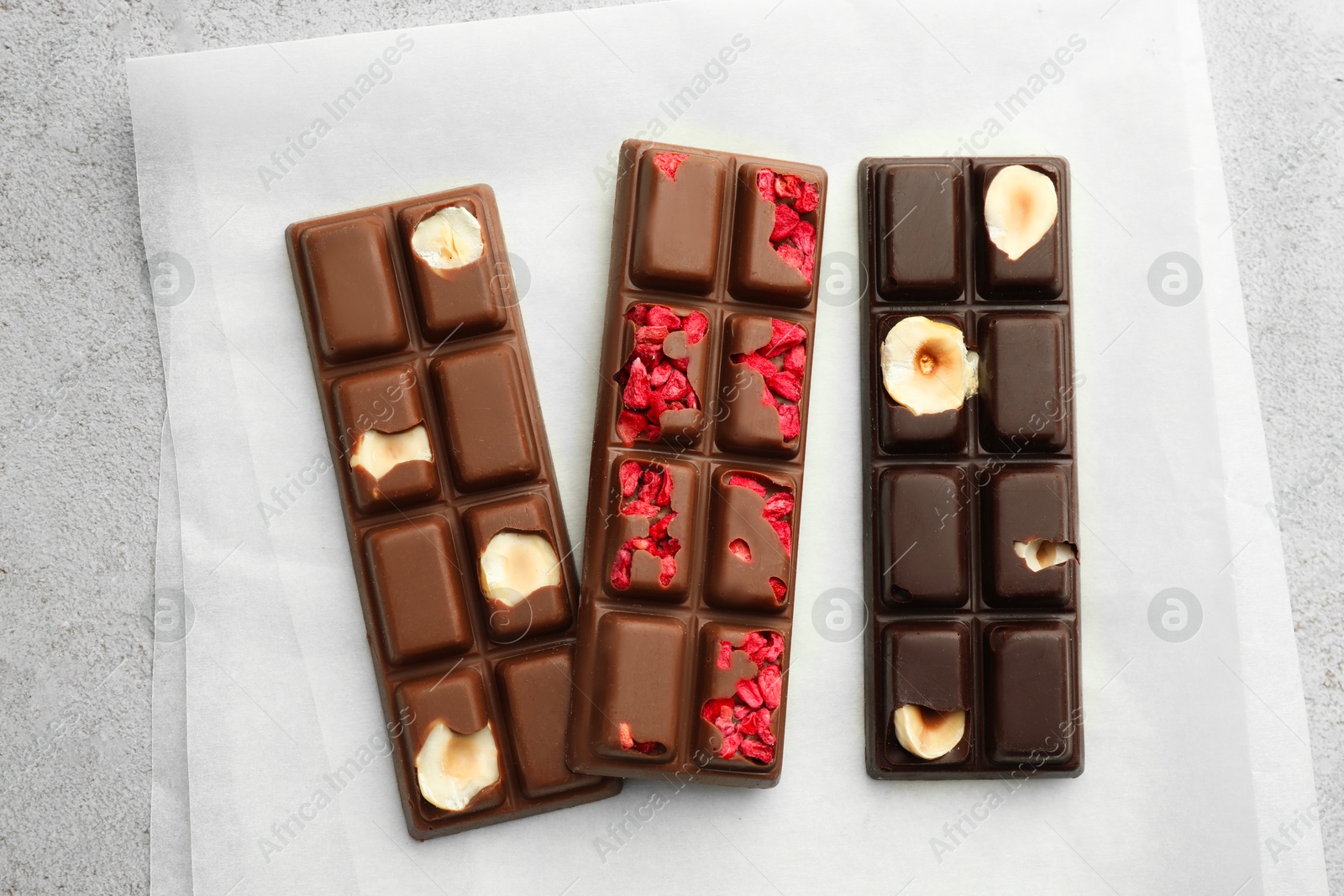 Photo of Delicious chocolate bars with different flavors on light table, flat lay