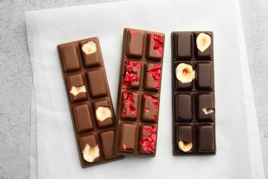 Delicious chocolate bars with different flavors on light table, flat lay