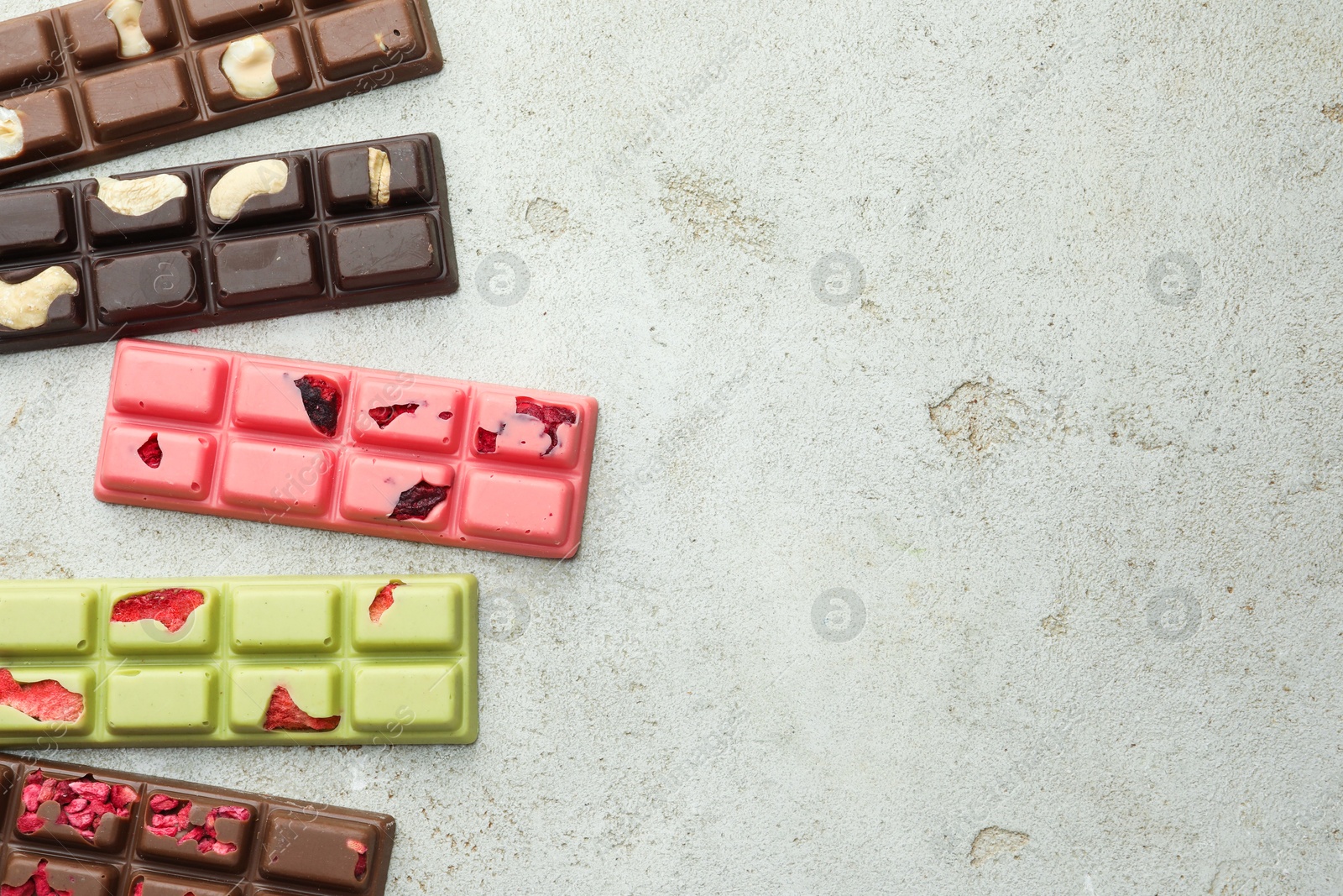 Photo of Delicious chocolate bars with different flavors on light table, flat lay. Space for text