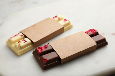 Photo of Delicious chocolate bars with different flavors on light table, closeup