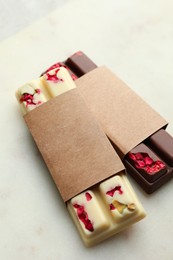 Delicious chocolate bars with different flavors on light table, closeup