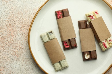 Delicious chocolate bars with different flavors on light textured table, top view