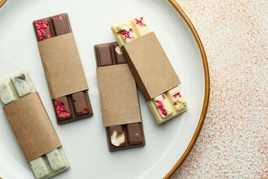 Delicious chocolate bars with different flavors on light textured table, top view