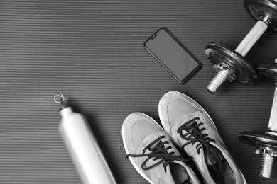 Photo of Smartphone and gym equipment on fitness mat, flat lay. Space for text