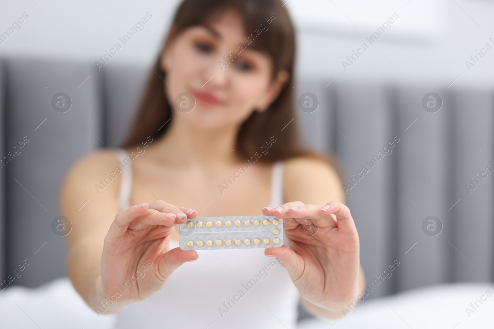 Photo of Woman with blister of contraceptive pills indoors, selective focus