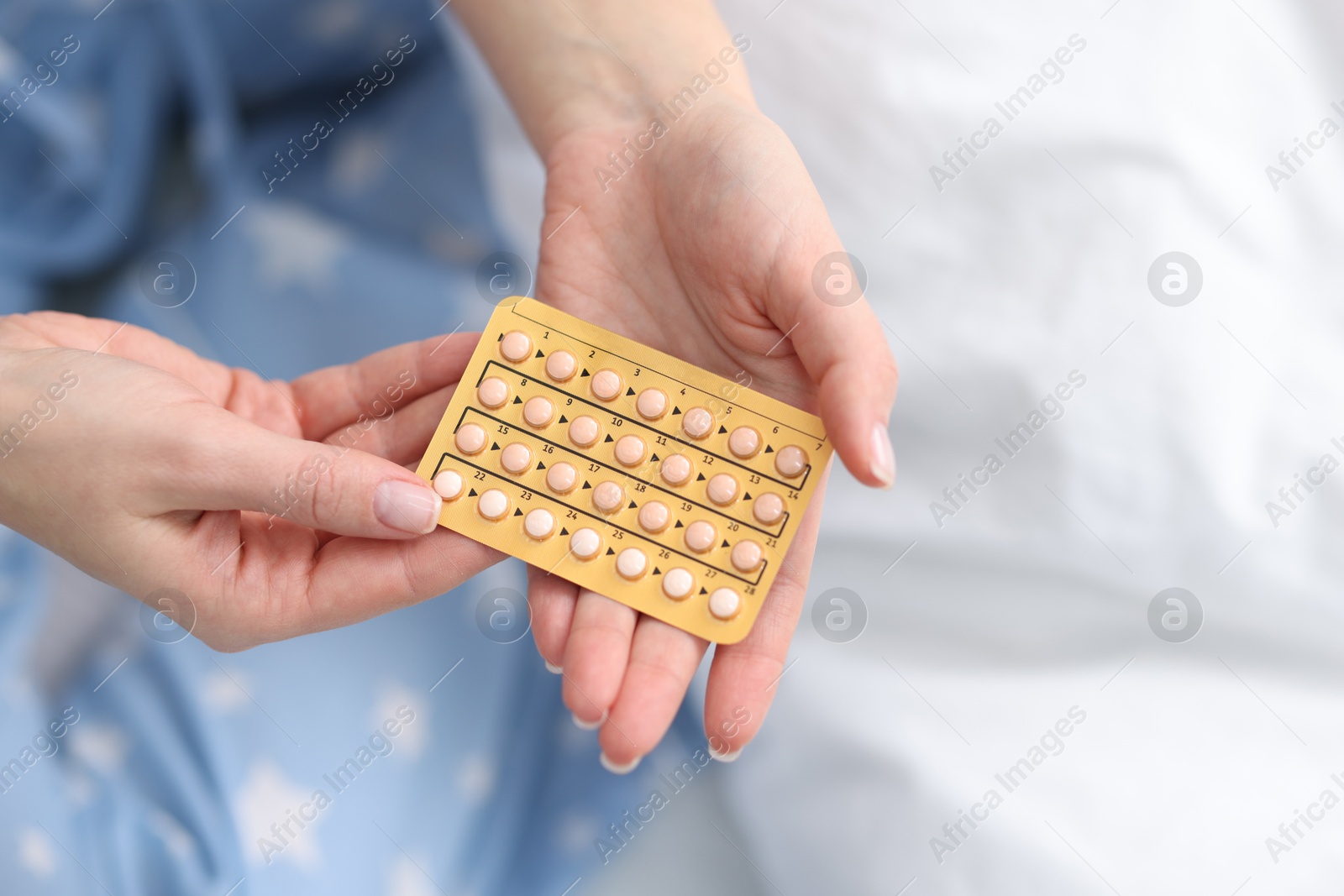 Photo of Woman with blister of contraceptive pills on bed, closeup. Space for text