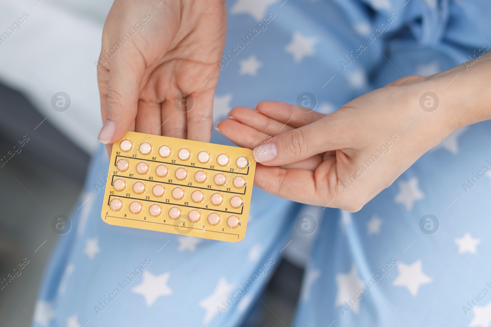 Photo of Woman with blister of contraceptive pills on bed, top view