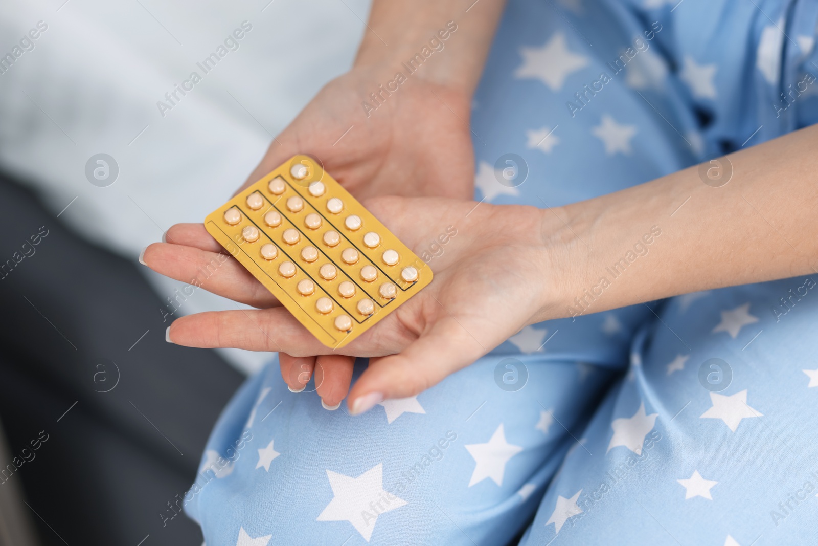 Photo of Woman with blister of contraceptive pills on bed, closeup