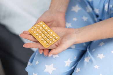 Photo of Woman with blister of contraceptive pills on bed, closeup