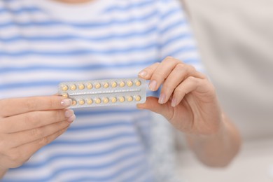 Photo of Woman with blister of contraceptive pills indoors, closeup