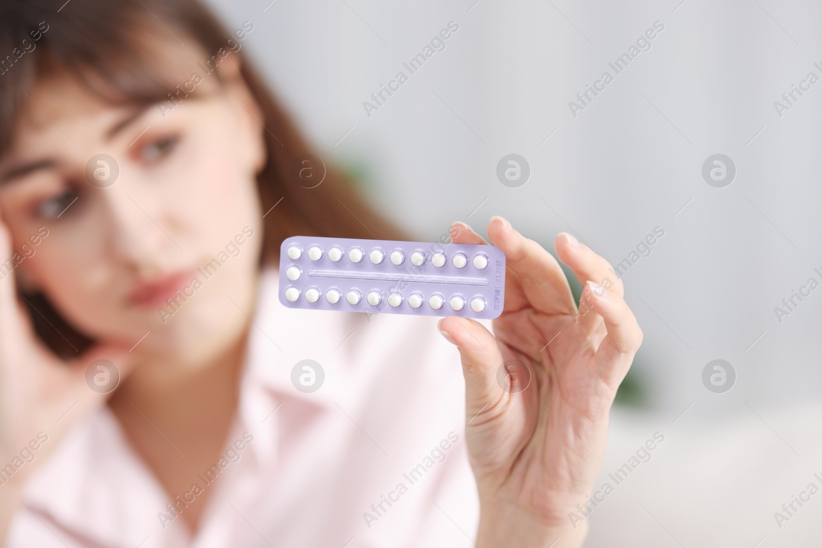 Photo of Woman with blister of contraceptive pills indoors, selective focus