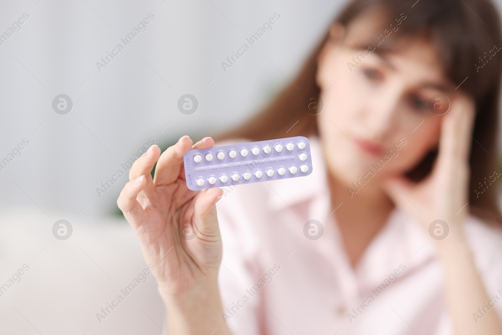 Photo of Woman with blister of contraceptive pills indoors, selective focus