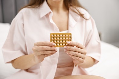 Photo of Woman with blister of contraceptive pills indoors, closeup