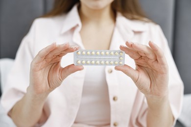 Photo of Woman with blister of contraceptive pills indoors, closeup