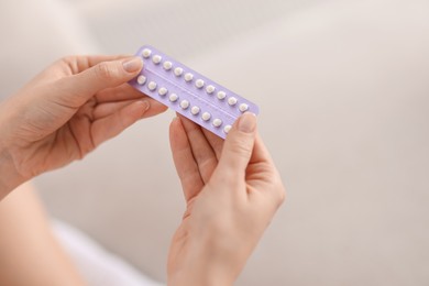 Photo of Woman with blister of contraceptive pills indoors, closeup. Space for text