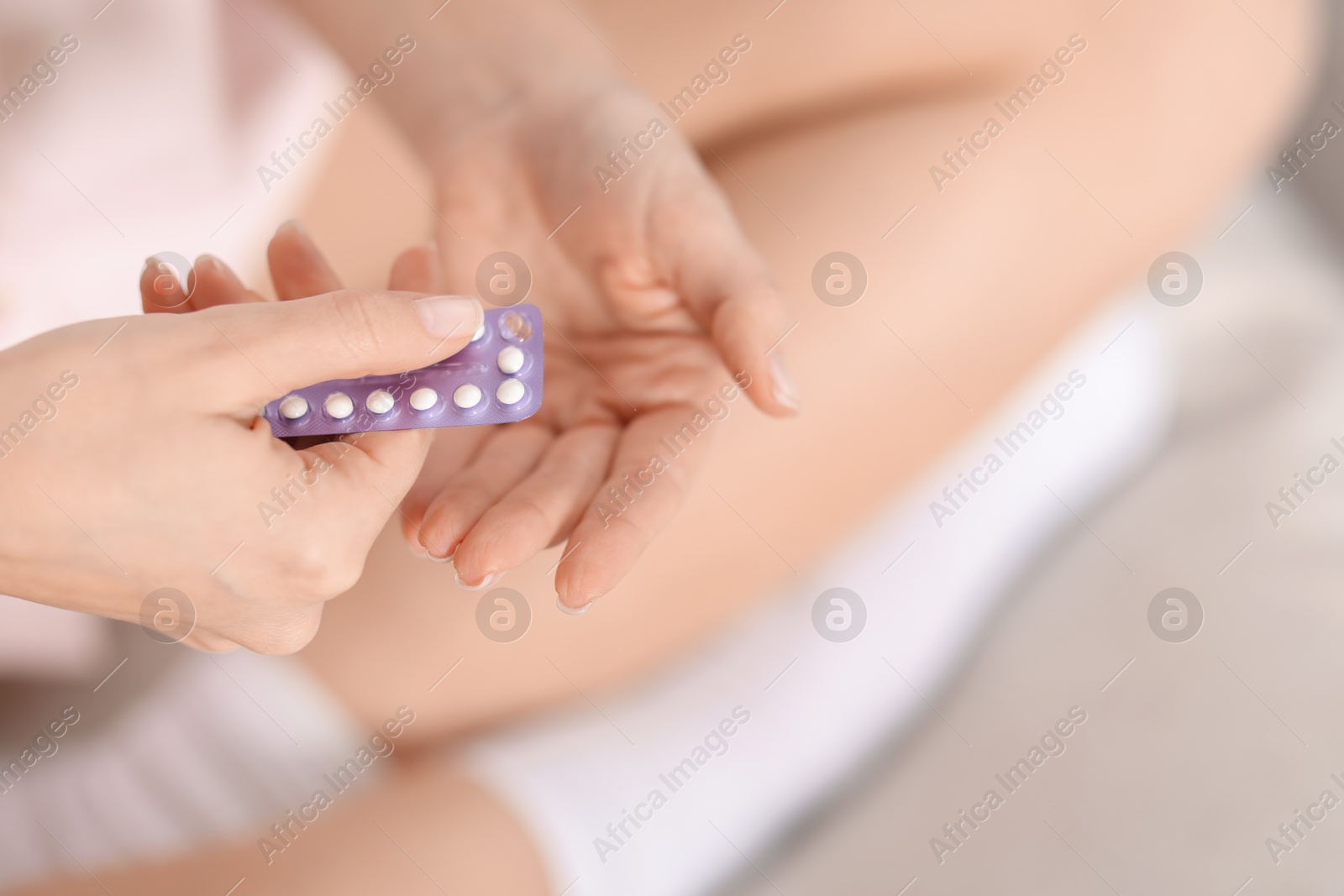 Photo of Woman taking contraceptive pill out from blister, closeup