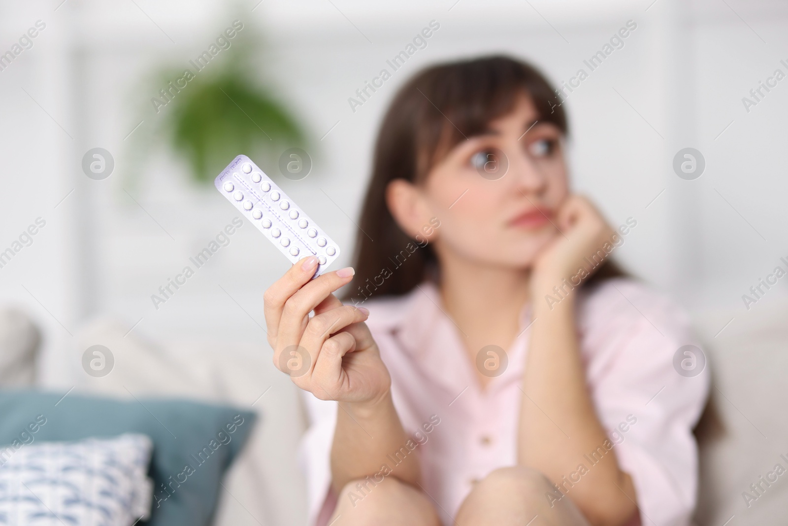 Photo of Woman with blister of contraceptive pills indoors, selective focus