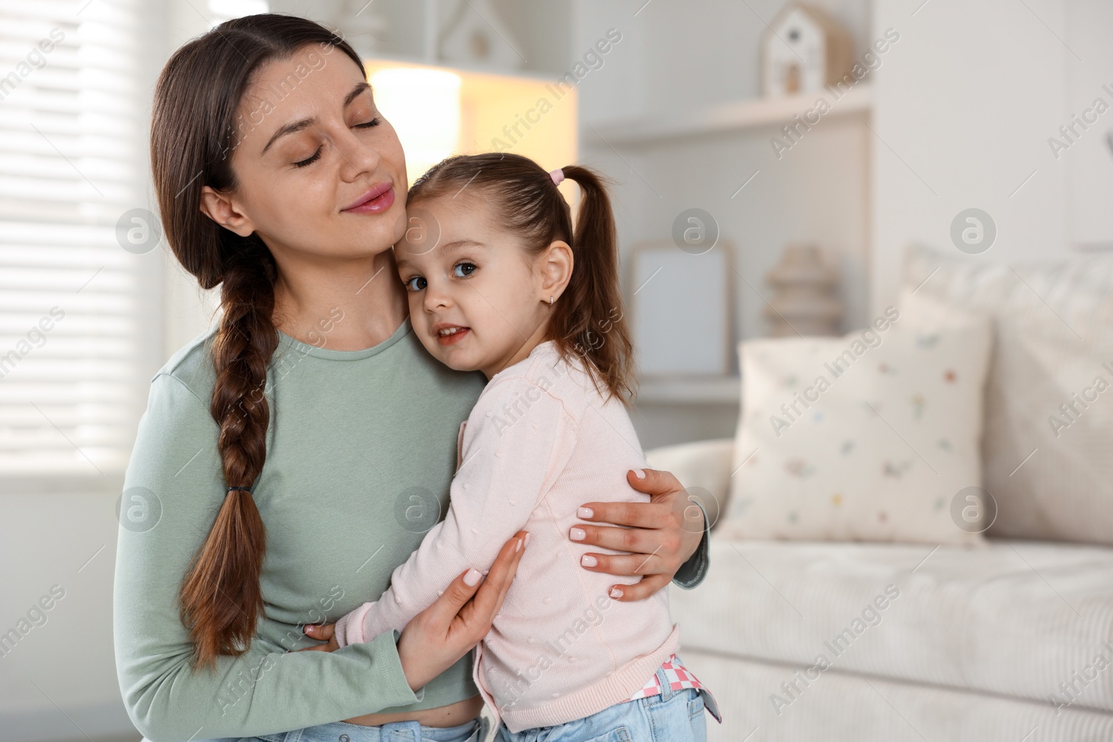 Photo of Family portrait of beautiful mother with little daughter at home. Space for text