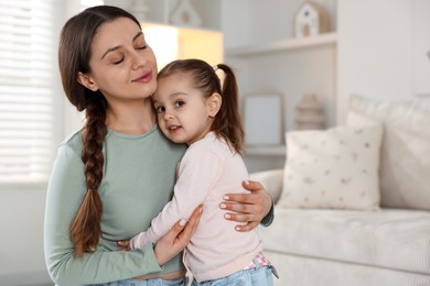 Family portrait of beautiful mother with little daughter at home. Space for text