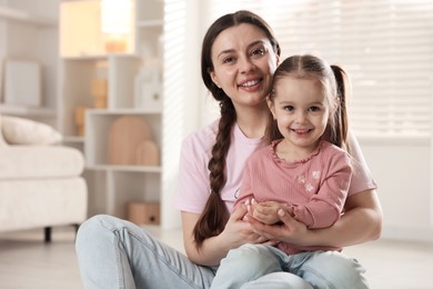 Family portrait of beautiful mother with little daughter at home. Space for text