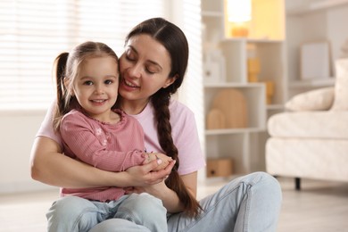 Photo of Family portrait of beautiful mother with little daughter at home. Space for text