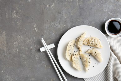 Photo of Delicious gyoza dumplings with sesame seeds served on grey table, top view. Space for text