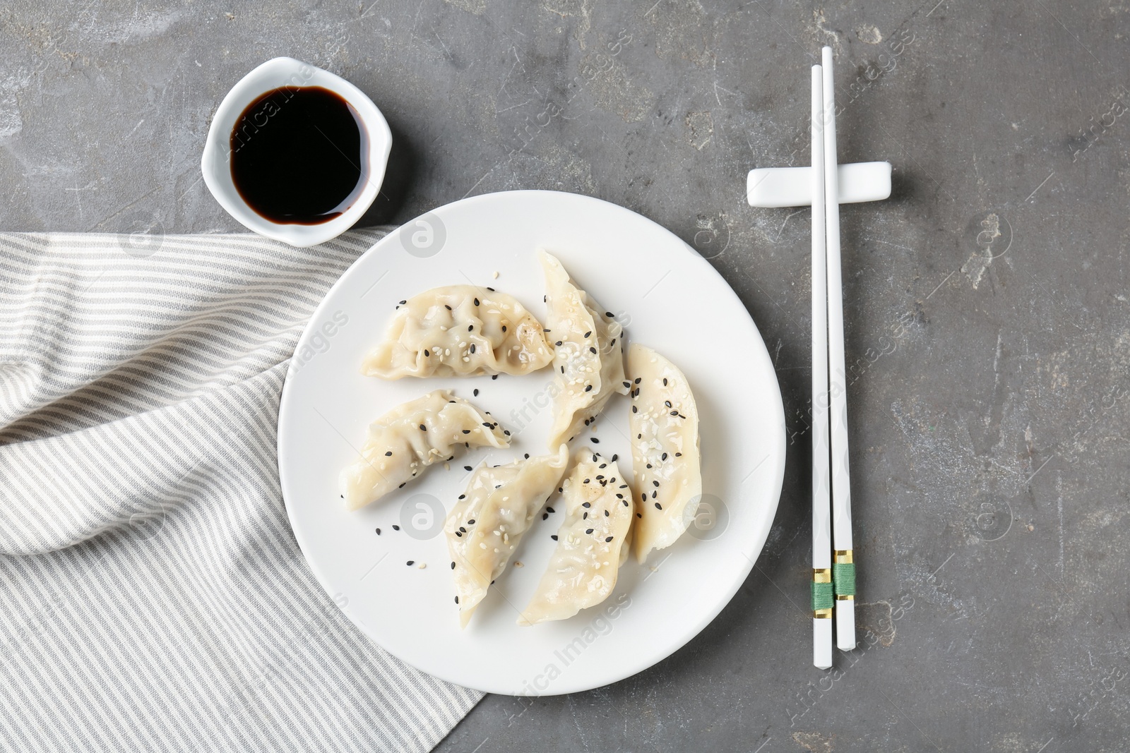 Photo of Delicious gyoza dumplings with sesame seeds served on grey table, top view