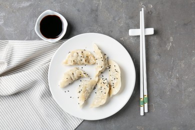 Photo of Delicious gyoza dumplings with sesame seeds served on grey table, top view