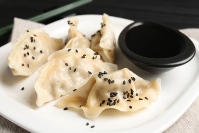 Photo of Delicious gyoza dumplings with sesame seeds served on table, closeup