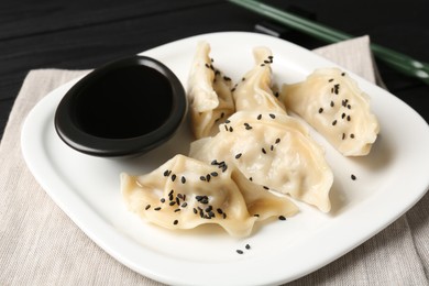 Photo of Delicious gyoza dumplings with sesame seeds served on table, closeup