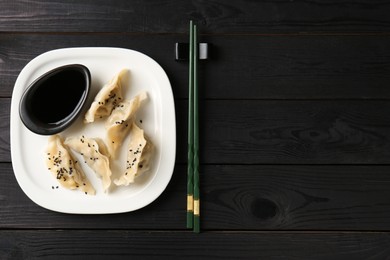 Photo of Delicious gyoza dumplings with sesame seeds served on table, top view. Space for text