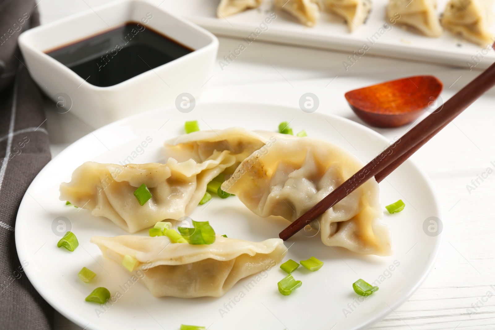 Photo of Eating tasty gyoza dumplings at white table, closeup