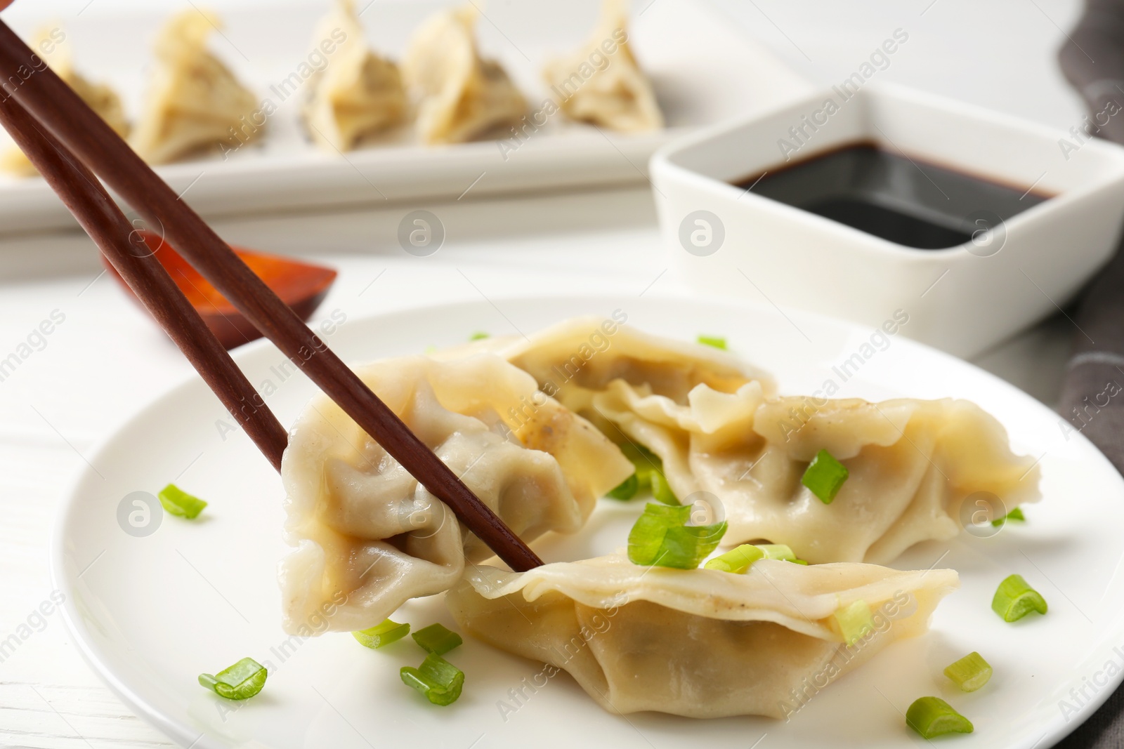 Photo of Eating tasty gyoza dumplings at white table, closeup