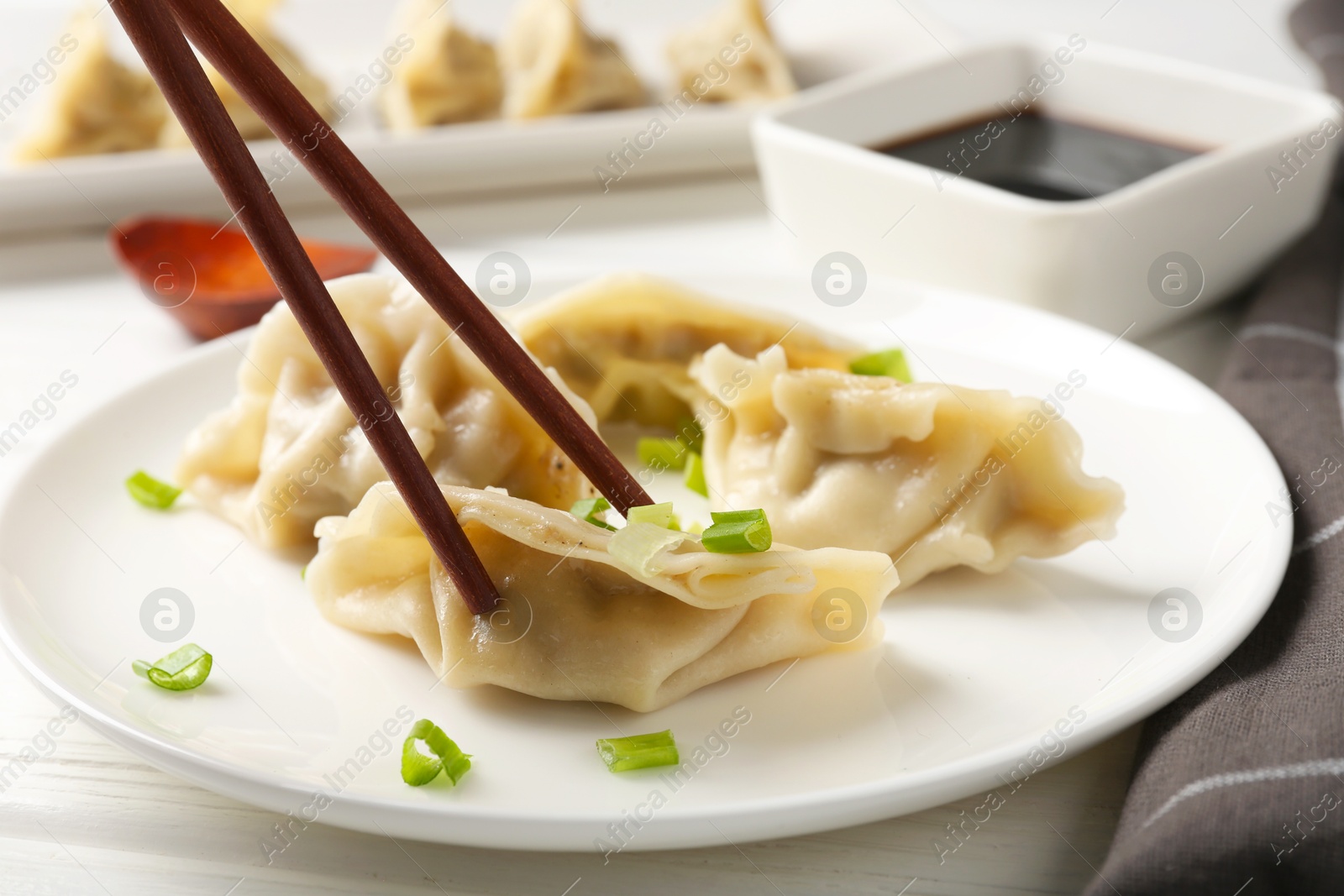 Photo of Eating tasty gyoza dumplings at white table, closeup