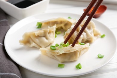 Photo of Eating tasty gyoza dumplings at white table, closeup