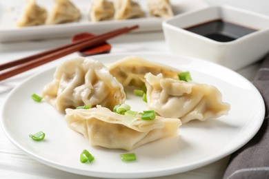 Photo of Delicious gyoza dumplings with chives served on white table, closeup