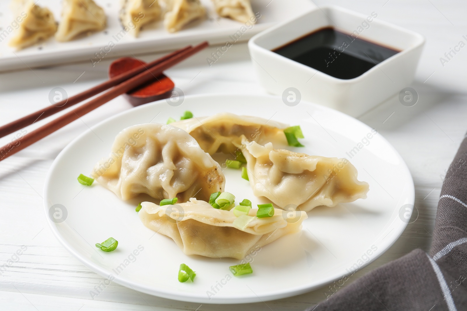 Photo of Delicious gyoza dumplings with chives served on white table, closeup