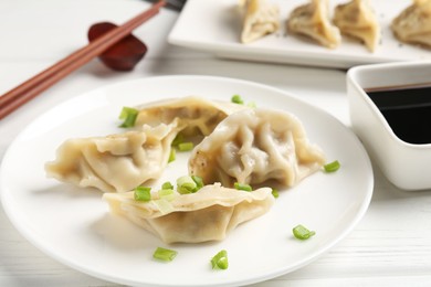 Photo of Delicious gyoza dumplings with chives served on white table, closeup