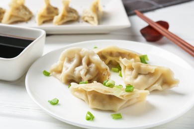 Photo of Delicious gyoza dumplings with chives served on white table, closeup