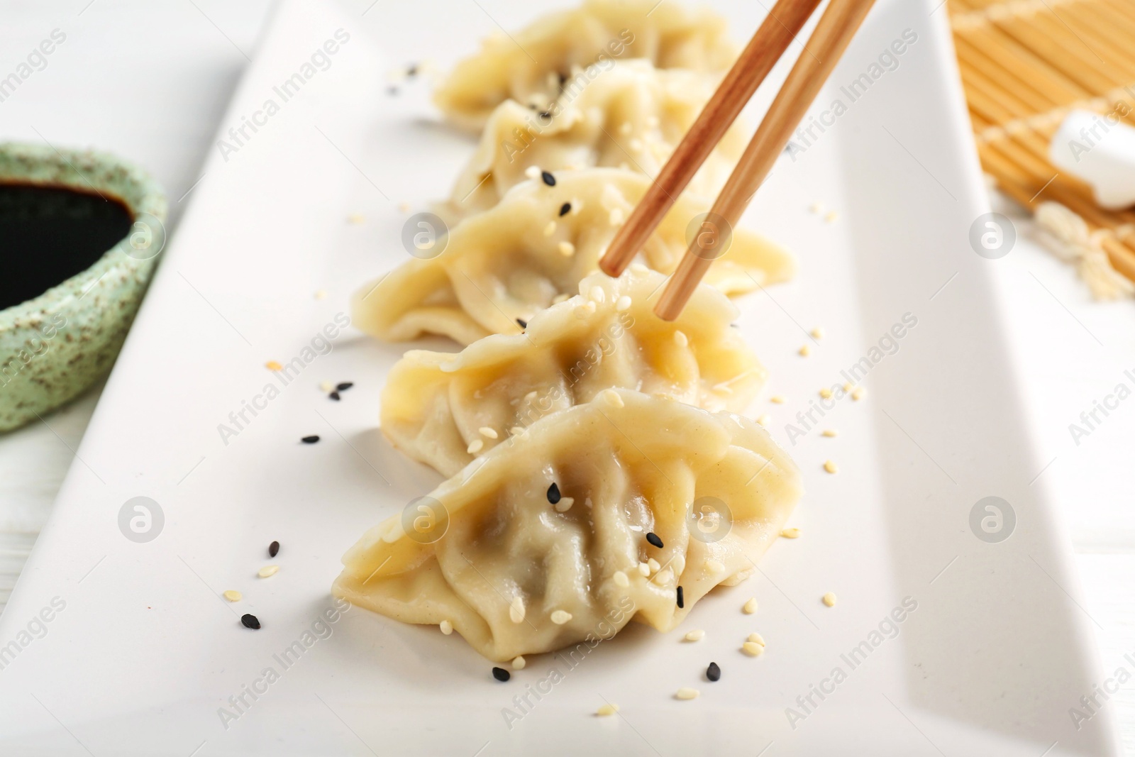 Photo of Eating tasty gyoza dumplings at white table, closeup