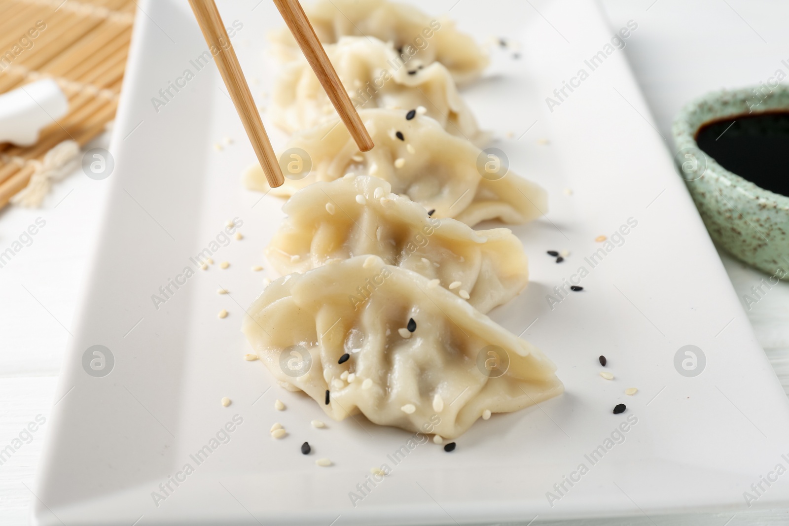 Photo of Eating tasty gyoza dumplings at white table, closeup