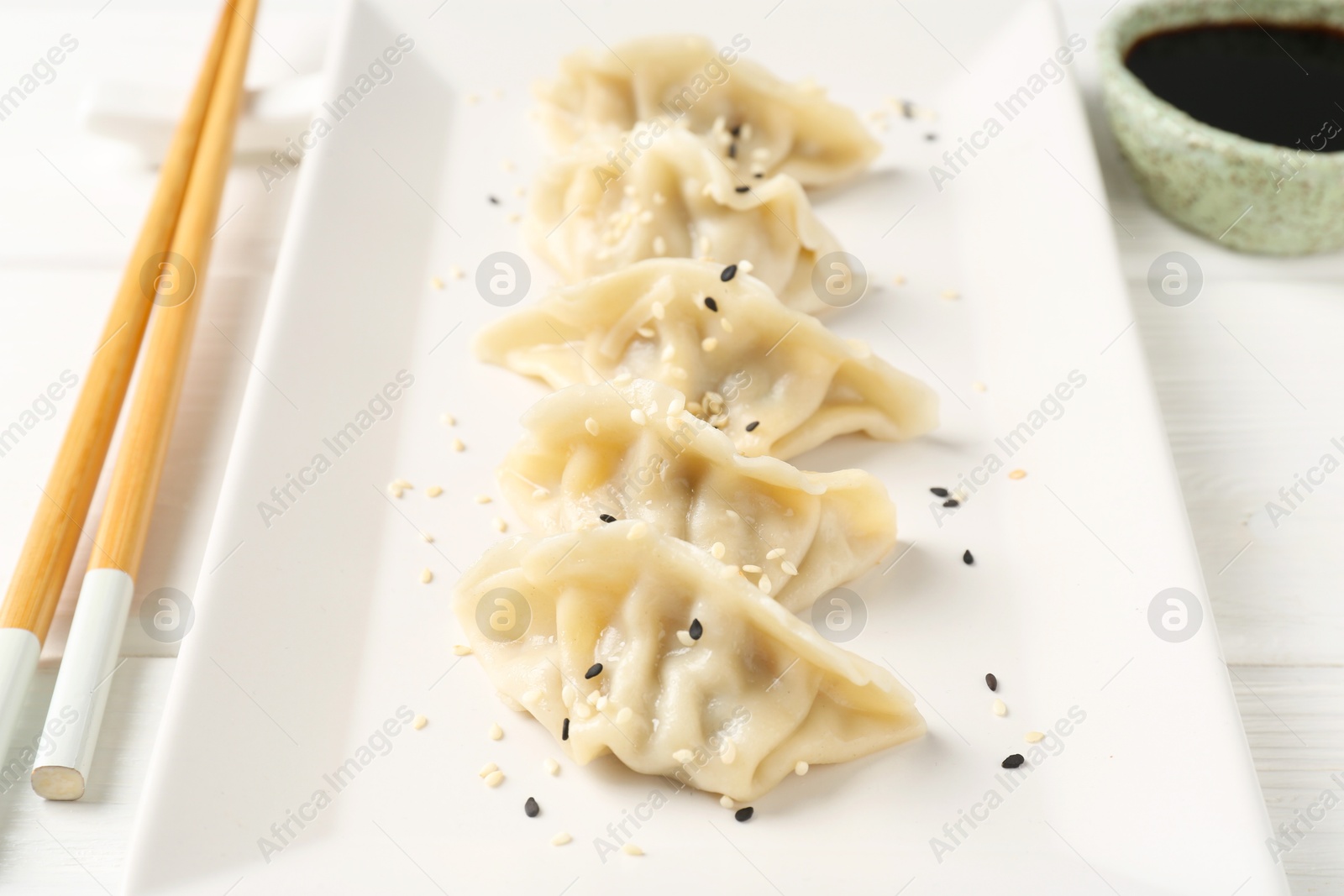 Photo of Delicious gyoza dumplings with sesame seeds served on white table, closeup