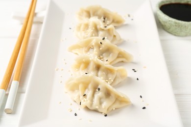 Photo of Delicious gyoza dumplings with sesame seeds served on white table, closeup