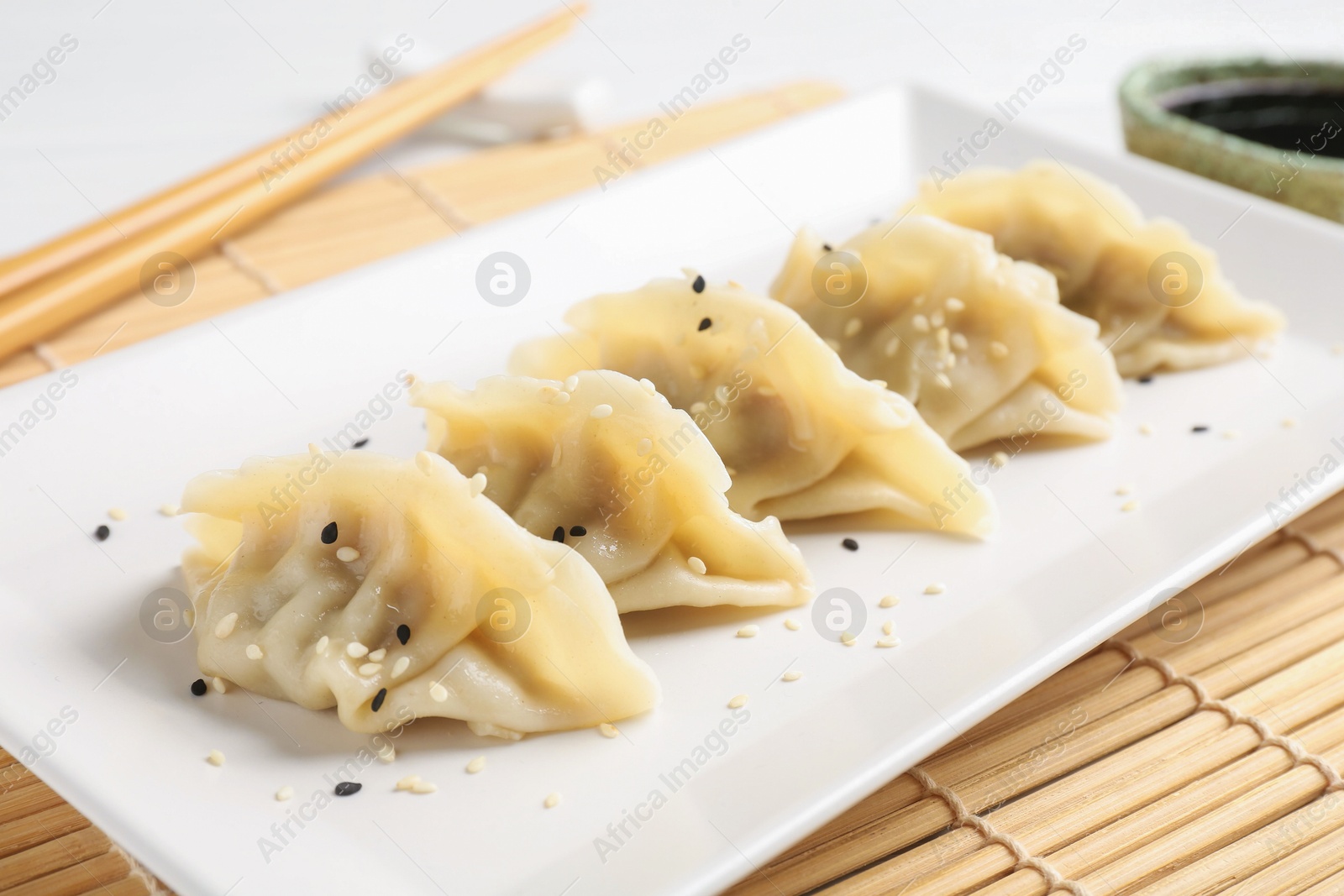 Photo of Delicious gyoza dumplings with sesame seeds served on table, closeup