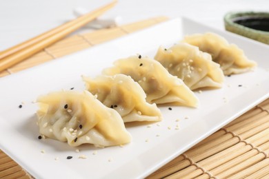 Photo of Delicious gyoza dumplings with sesame seeds served on table, closeup