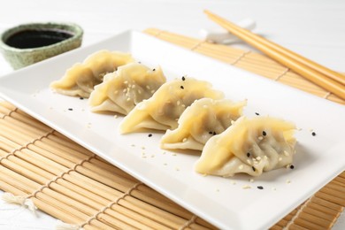 Photo of Delicious gyoza dumplings with sesame seeds served on table, closeup